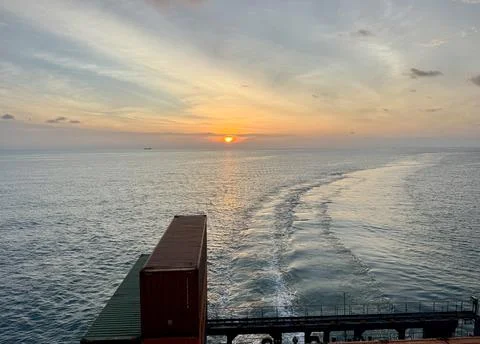 Sunset Wake Behind Cargo Ship at Sea Stock Photos