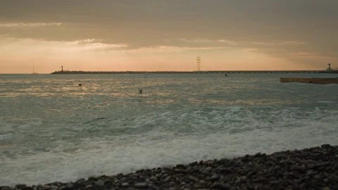 Sunset warm sky sea waves. Birds fly at Rocky beach. Sap surfing swimmer Stock Footage 167496562
