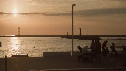 Sunset warm sky sea waves pier. Silhouettes of walking people crowd. Stock Footage 167496598