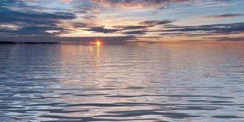 Sunset in water surface with waves under cloudy sky landscape Stock Photos