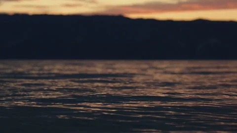 Sunset water waves surface reflection mountains Stock Footage 94106432