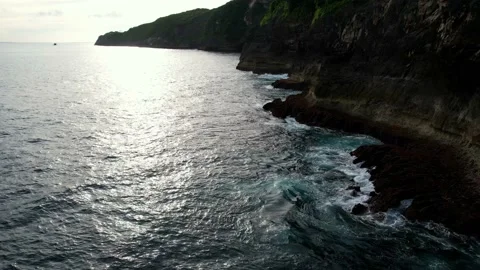 Sunset Waves Against Bali’s Rugged Cliffside Coastline Stockbeeldmateriaal 237996125