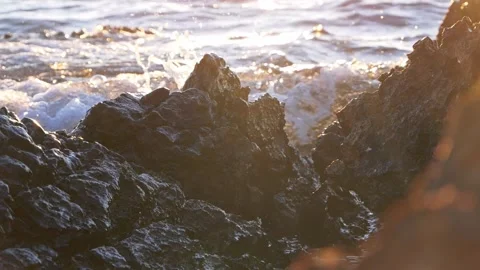 Sunset Waves Crashing Over Dark Rocky Shoreline With Golden Backlight Stock Footage 337419648