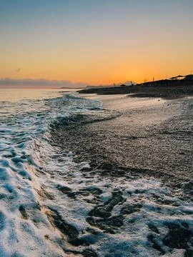 Sunset waves gently caressing golden shoreline, warm orange and pink tones Foto stock