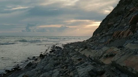 At sunset waves gently splash about the rocky shore. Stock Footage 80092608