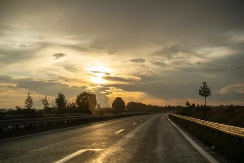 Sunset on a Wet Highway: Dramatic Sky and Road Reflecting Light Stock Photos