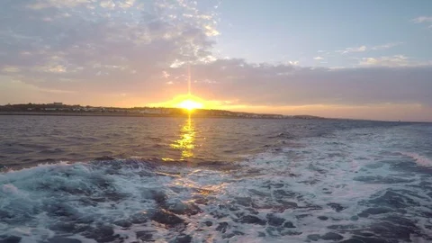 Sunset while traveling on a ship, waves from a yacht, in the background an Stock Footage 95247905