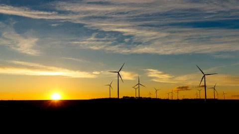 Sunset with windmills in background and blue sky. sunset in fields Stock Photos