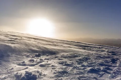 The sunset in winter during a wind storm with the snow being blown away on a  Foto stock