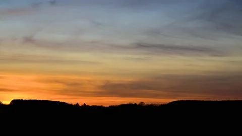 Sunset wispy grey clouds move from right to left in an orange and blue colored s Stock Footage 142391020