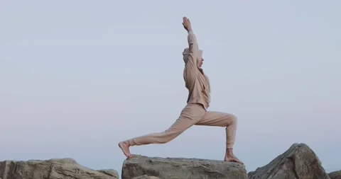 A sunset yoga session on large rocks by the sea promotes health and well-being.  Stock Footage 160048098