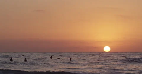 Sunsets while surfers wait to catch their last wave of the evening Stock Footage 68553052