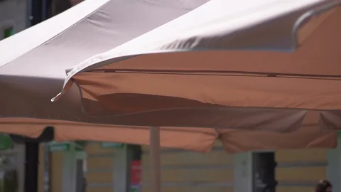 Sunshade over the tables of the summer open area of the restaurant on the city  Stock Footage 108776861