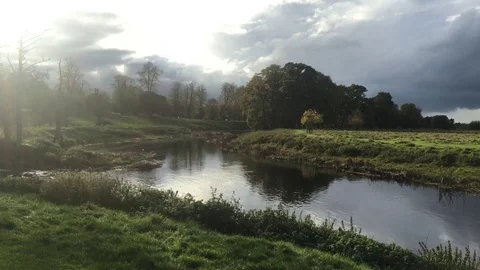Sunshine breaks through the clouds onto an English Riverside on an Autumn day Stock-Footage 84676539