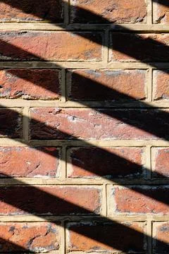 Sunshine casting a shadow pattern on a brick wall Stock Photos