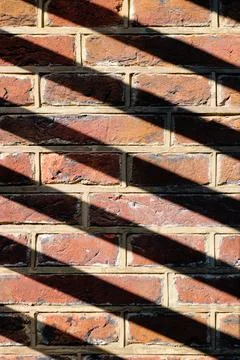 Sunshine casting a shadow pattern on a brick wall 写真素材