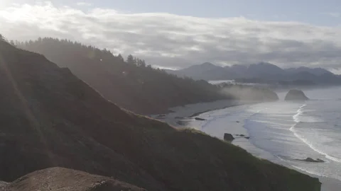 Sunshine glows over dramatic Cliffs Overlooking the Pacific Ocean at Canon Beach Stock Footage 332255069
