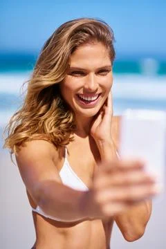 Sunshiny smiles. an attractive young woman enjoying a vacation at the beach. Stock Photos