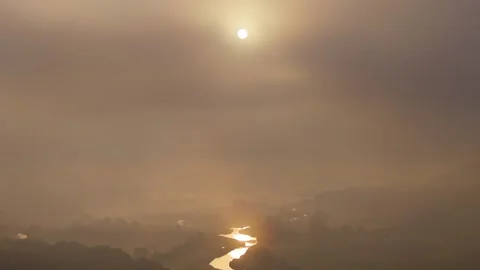 Sunspot Diffused by Thick Clouds and Fog with Reflection on River During Stock Footage 340855661