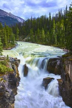 Sunwapta Falls Waterfall Surrounded by Forest and Mountain Landscape in Canada Foto stock