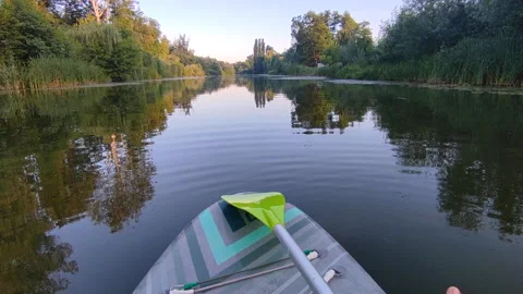 SUP board with green paddle on the surface of the river water with green trees Stock Footage 287710246