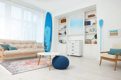 SUP board, shelving unit with different decor elements, table and pouf in r.. Stock Photos