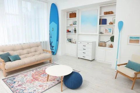 SUP board, shelving unit with different decor elements, table and pouf in r.. Stock Photos