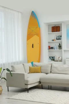 SUP board, shelving unit with different decor elements and stylish sofa in .. Stock Photos