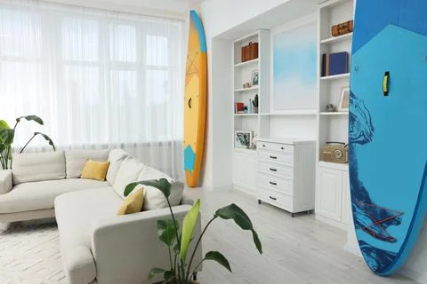 SUP boards, shelving unit with different decor elements and stylish sofa in.. Stock Photos