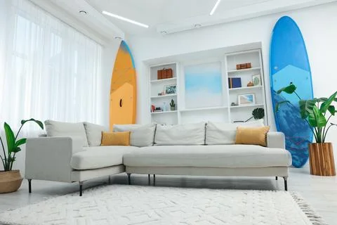 SUP boards, shelving unit with different decor elements and stylish sofa in.. Stock Photos