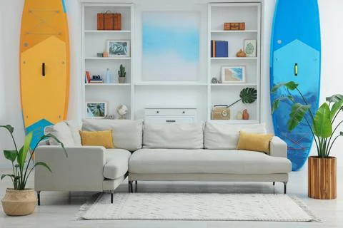 SUP boards, shelving unit with different decor elements and stylish sofa in.. Stock Photos
