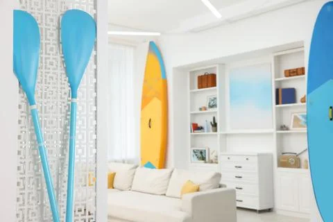 SUP boards, shelving unit with different decor elements and stylish sofa in.. Stock Photos
