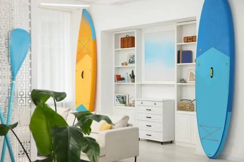 SUP boards, shelving unit with different decor elements and stylish sofa in.. Stock Photos