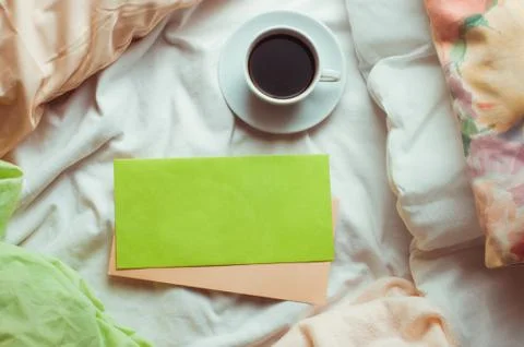 Сup of coffee in a bed with empty postal envelopes Stock Photos