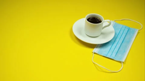 Сup of espresso on yellow background next to blue protective mask Stock Footage 140360883