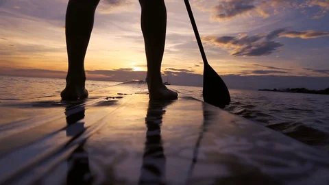 SUP paddle board on the beach, close up of legs and paddle, low angle Stock Footage 109180047