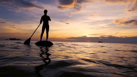 SUP, silhouette of man, Standup paddleboarding at sunset,  beach sport leisure Stock Footage 93643953