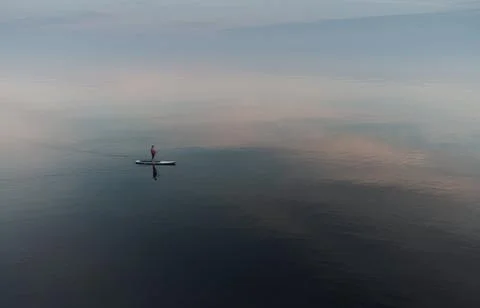 SUP surfer floats in an open calm sea. Aerial view Stock Photos