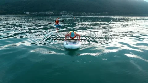 A SUP-surfer girl does push-ups, swims on a board with a paddle on the sea at Stock Footage 247849999