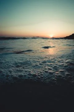 Super close up of the bubbles in the tide of the beach during a sunset Stock Photos