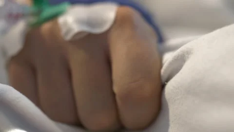 Super close-up of a Caucasian hand with drip in hospital bed clutching the Stock Footage 218278335
