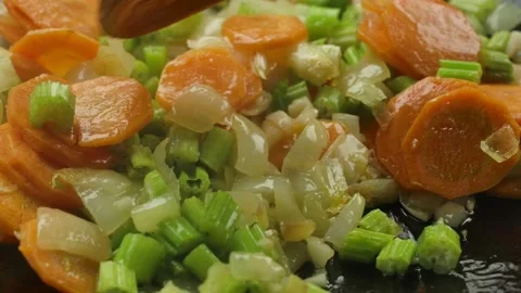 Super close-up of celery and carrot slices and white onion cubes mixed on pan Stock Footage 231994652