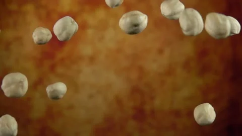 Super close-up of peeled hazelnuts bouncing on a yellow ochre background Stock Footage 148870558