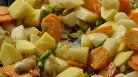 Super close-up of pumpkin cubes falling on the vegetables roasting on the pan Video stock 234136788