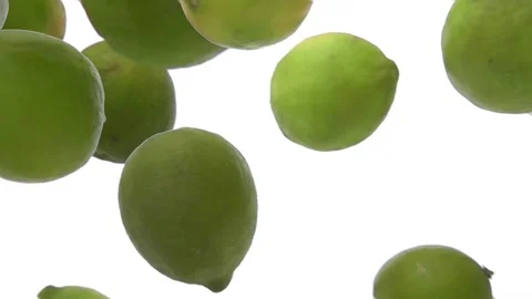 Super close-up of the ripe limes falling down on the white background Stock Footage 213228026