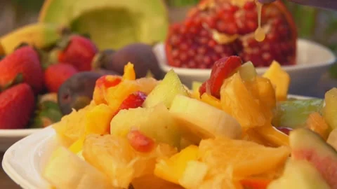 Super close-up of salad made of oranges, figs, strawberries falling on a plate Stock Footage 169606376