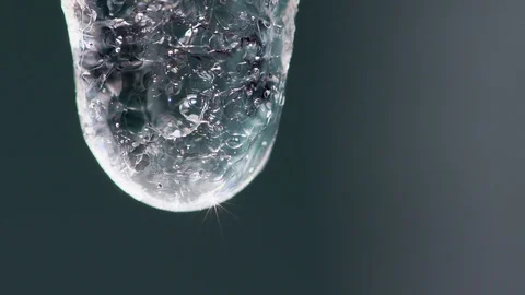 Super close-up slow motion video of a crystal drop dripping from an icycle Stock Footage 90637135