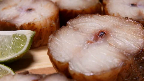 Super close-up of smoked eel pieces with lime slices lying on a wooden board Stock Footage 161067226