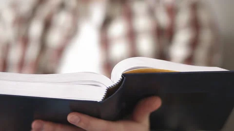 Super close up student guy with a book in hands sits on sofa preparing for a Stock Footage 131933350
