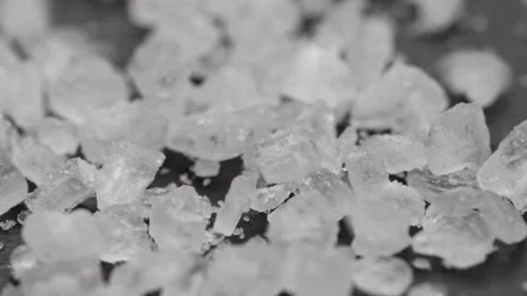 Super macro shot of salt crystals falling on black stone surface. Slider shot of Stock Footage 252284324